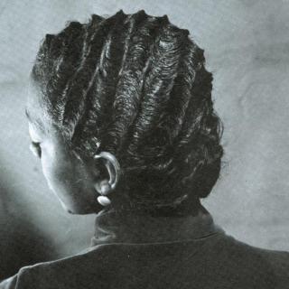 Historic photograph of the back of a woman's head, her hair is coiffed with finger waves and she is wearing a collared shirt and a circular earring.