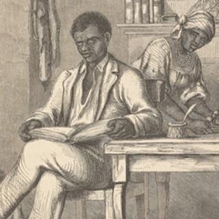 A man sitting at a table reading a book.