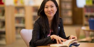 Photo of a library patron sitting at a table with a book in her hands