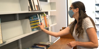 Photo of a patron grabbing a book from a library shelf