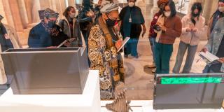A group of people stand around a display case while holding notebooks and gazing at the artifacts within.